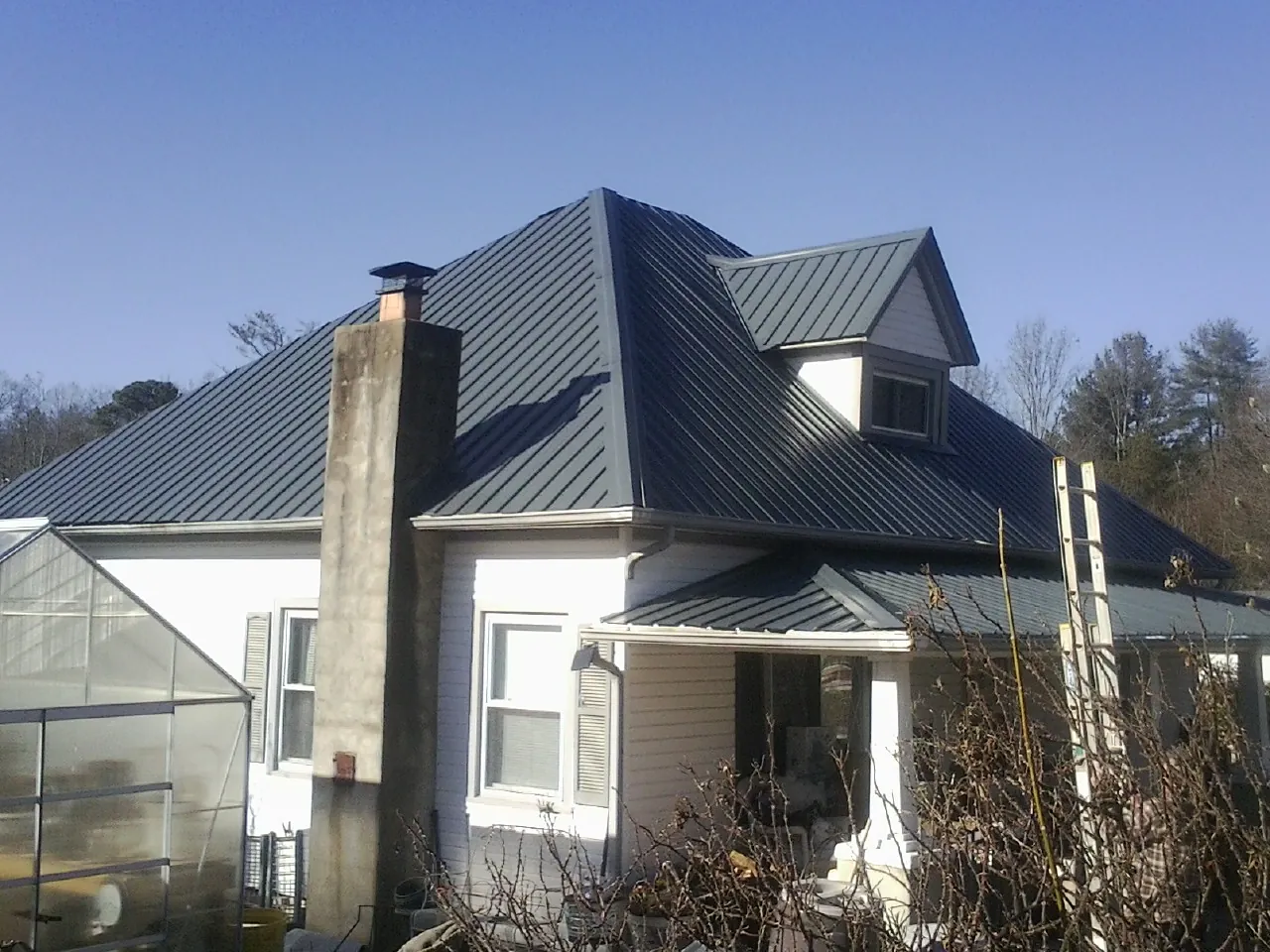 Dark blue standing seam metal roof on a white farmhouse with dormer — Slate & Tile Roof Repair by Roofing Brothers in Hinsdale